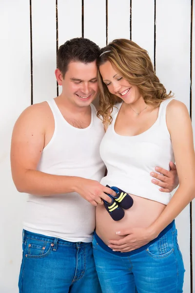 Warten auf das Baby. kleine Babyschuhe in den Händen von Papa auf dem Bauch meiner Mutter. — Stockfoto