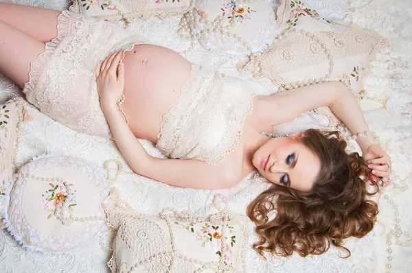 Güzel hamile kadın kanepede yatan lüks saç siyah. Üstten Görünüm — Stok fotoğraf