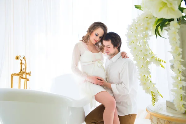 Piękna kobieta w ciąży z mężem, przytulanie jej brzuch w łazience — Zdjęcie stockowe