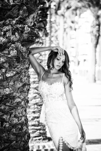 Braut in einem schönen Hochzeitskleid, junge sexy Frau auf einem Hintergrund von Palmen. — Stockfoto