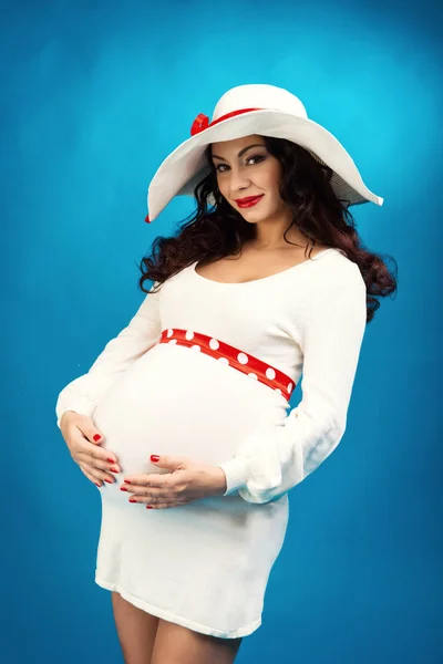 Красивая беременная женщина в белом платье на синем фоне — стоковое фото