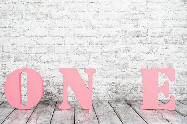 Büyük pembe harflerle bir beyaz duvara karşı.