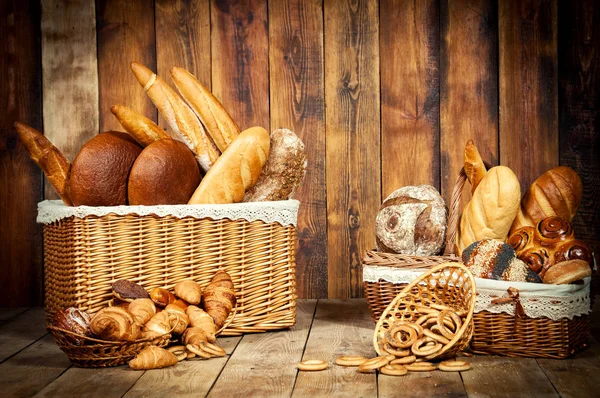 Verschiedenes Brot mit Ohren im Korb auf Holzgrund. — Stockfoto