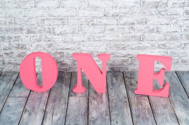 Büyük pembe harflerle bir beyaz duvara karşı.