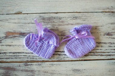 Ahşap bir arka plan üzerinde mor tığ işi bebek çorap.
