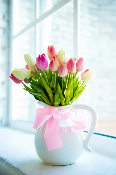 Beautiful motley tulips in a white vase against the window. — Stock Photo, Image