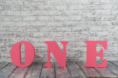 Büyük pembe harflerle bir beyaz duvara karşı.