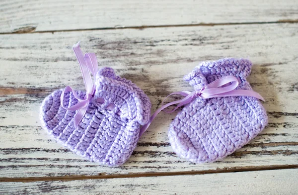 Chaussettes bébé au crochet violet sur un fond en bois . — Photo