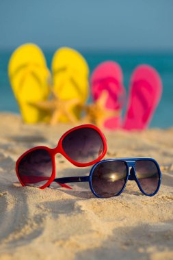 Sarı ve pembe sandalet gözlükle deniz arka planı kum stand