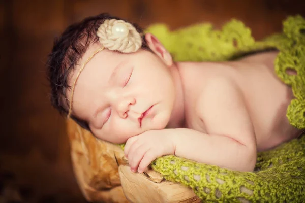 A koszorú, a kúpok és a bogyók meglehetősen újszülött gyermek fekszik a csonkot, és alszik. — Stock Fotó