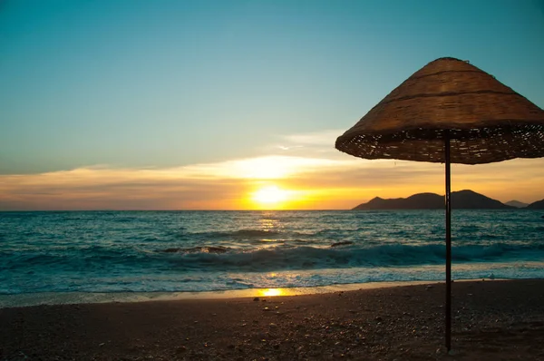 Sombrilla de playa en el fondo del mar y puesta de sol — Foto de Stock