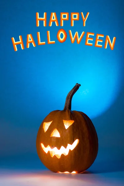 Citrouille d'Halloween, silhouette de drôle de visage sur fond bleu . — Photo