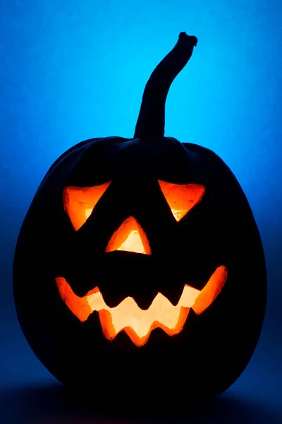 Halloween pompoen, silhouet van grappig gezicht op blauwe achtergrond. — Stockfoto