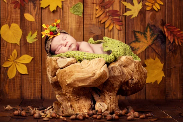 เด็กทารกที่เกิดใหม่ที่น่ารักในพวงของก้อนและผลเบอร์รี่อยู่บนตอไม้และหาว . — ภาพถ่ายสต็อก