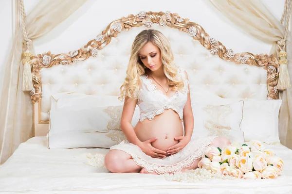 lotus pozisyonunda bir yatakta oturmuş güzel hamile esmer