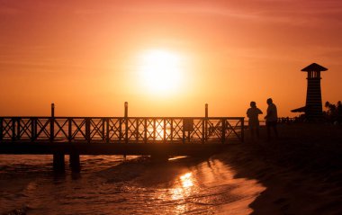 Denizin üzerinde gün batımı. Ön planda iskele.