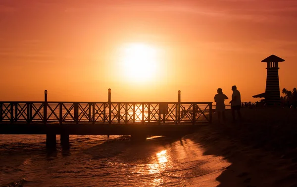 Denizin üzerinde gün batımı. Ön planda iskele.