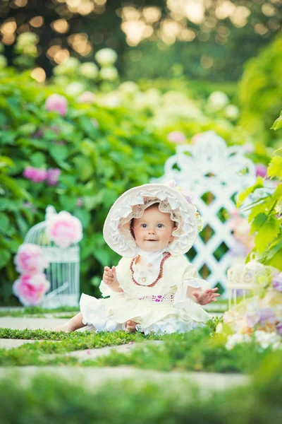 Beautiful little girl in a white dress and hat in a spring garden. — Stock Photo, Image