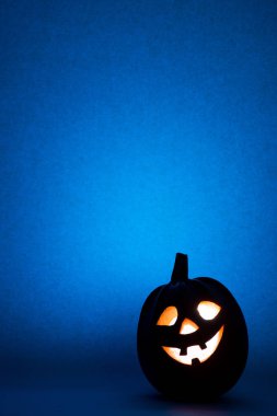 Mutlu Halloween kabak, mavi arka plan üzerinde komik surat silüeti.