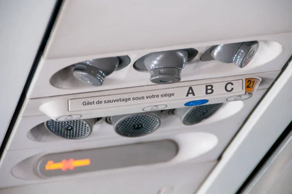 Plane inside interior. Overhead board with sign no smoking and fasten seatbelt, nobody. Blue tone — Stock Photo, Image
