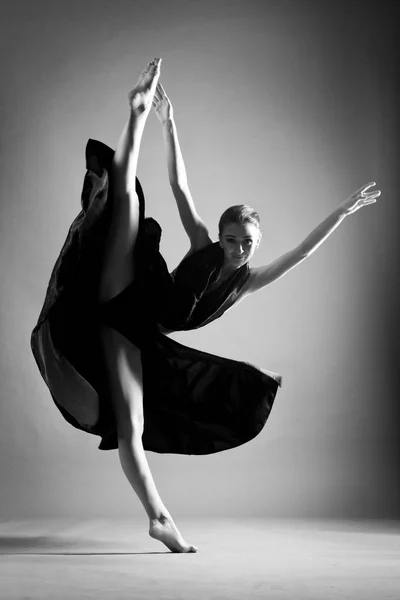 Uma linda garota atlética em um vestido preto está dançando. No salto — Fotografia de Stock