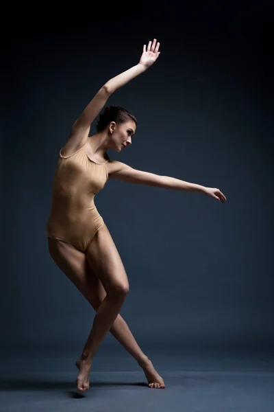 Uma linda garota atlética em um vestido preto está dançando. Em movimento — Fotografia de Stock