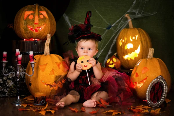 Küçük cadı kız çocuk gülüyor kabaklar ve mumlar arasında.
