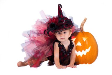 Küçük cadı kız çocuk gülüyor kabaklar ve mumlar arasında beyaz bir arka plan üzerinde.