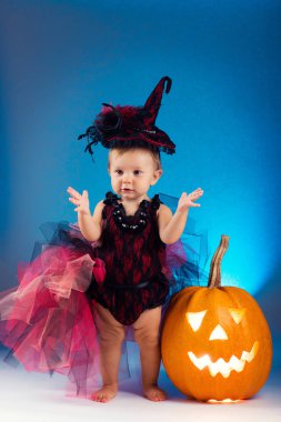 Küçük cadı kız çocuk gülüyor kabaklar ve mumlar arasında