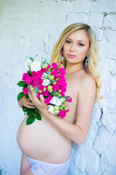 Bela senhora grávida com um buquê de flores esperando o bebê. Gravidez . — Fotografia de Stock