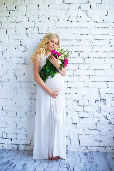 Mooie zwangere dame met een boeket van bloemen te wachten voor de baby. Zwangerschap. — Stockfoto