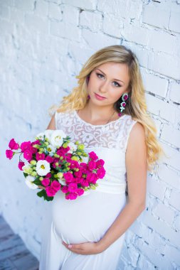 Bir buket çiçek bebek için bekleyen ile güzel hamile bayan. Gebelik.