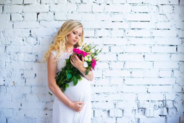 Bir buket çiçek bebek için bekleyen ile güzel hamile bayan. Gebelik.