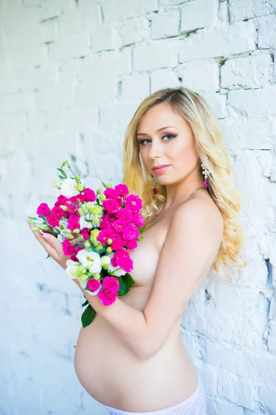 Bela senhora grávida com um buquê de flores esperando o bebê. Gravidez . — Fotografia de Stock