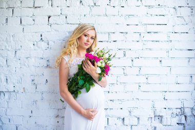 Bir buket çiçek bebek için bekleyen ile güzel hamile bayan. Gebelik.