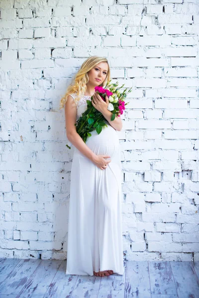 Прекрасная беременная женщина с букетом цветов ждет ребенка. Беременность . — стоковое фото