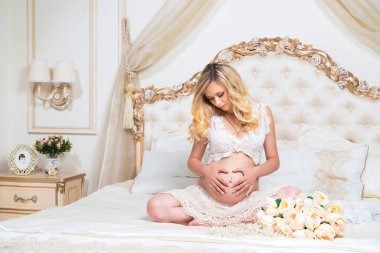 lotus pozisyonunda bir yatakta oturmuş güzel hamile esmer