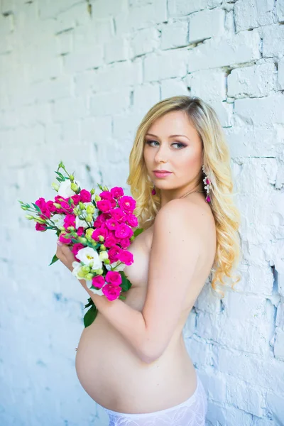 Vackra gravid dam med en bukett blommor som väntar på barnet. Graviditet. — Stockfoto