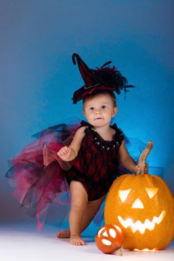 Küçük cadı kız çocuk gülüyor kabaklar ve mumlar arasında