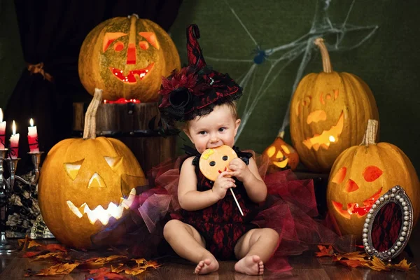 Küçük cadı kız çocuk gülüyor kabaklar ve mumlar arasında.