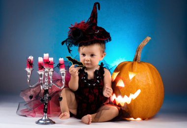 Küçük cadı kız çocuk gülüyor kabaklar ve mumlar arasında.