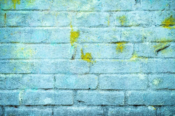 Bakgrund och tapet eller konsistens av en blå tegelvägg med fläckar av gul färg. — Stockfoto