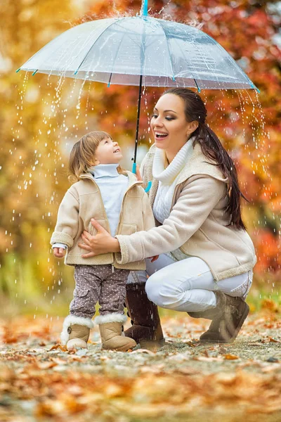 Mom and daughter under the umbrella hide from the rain. — Stock Photo, Image