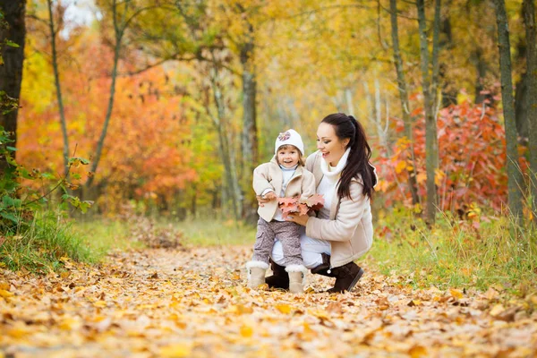 Dziewczynka i jej matka bawią się w jesiennym parku — Zdjęcie stockowe