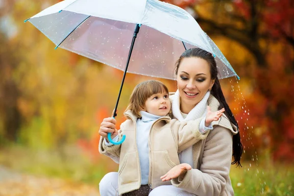Мама и дочь под зонтиком прячутся от дождя . — стоковое фото