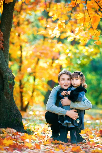 Gelukkig broer en zus zitten op de bank praten en lachen. In de natuur, wandelen in de open lucht. — Stockfoto