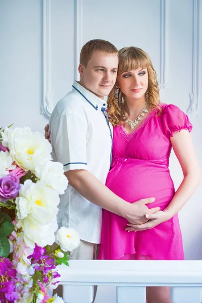 Feliz futuro padre con una hermosa mujer embarazada linda con flores . —  Fotos de Stock