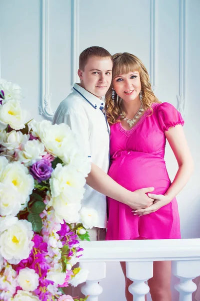 Gelukkig toekomstige vader met een prachtige leuke zwangere vrouw met bloemen. — Stockfoto