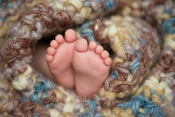 Pequeno bebê pernas em um cachecol cinza — Fotografia de Stock