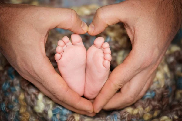 Picioare mici ale unui copil în inimă din mâinile tatălui — Fotografie, imagine de stoc